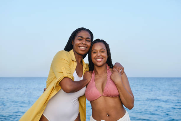 istock Two smiling black young women embracing on the beach 2205884573