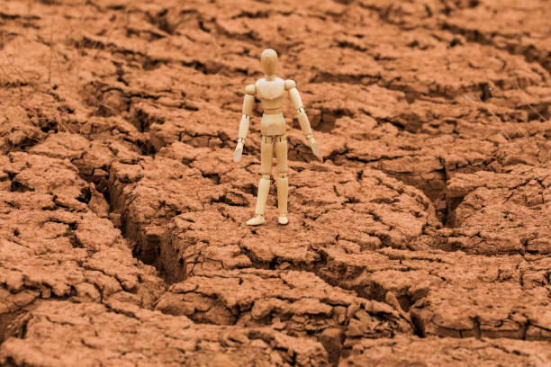 istock Wooden Mannequin Standing On Cracked Earth, Global Warming Concept 2205888291