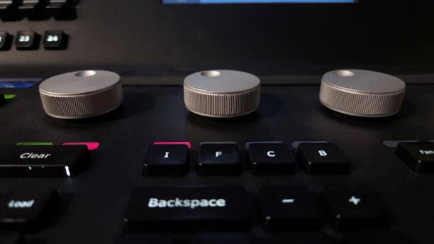 istock Close-up of a professional lighting control panel with illuminated buttons, rotary dials, and a dark keyboard. 2205888338