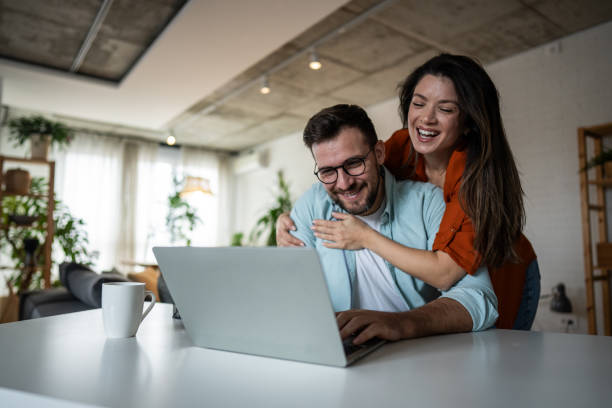 istock Happy couple laughing and using laptop at home 2205891611