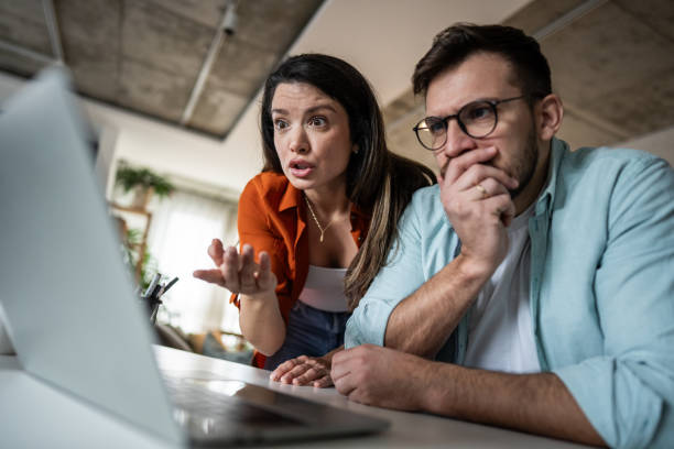 istock Shocked couple looking at laptop at home 2205891803