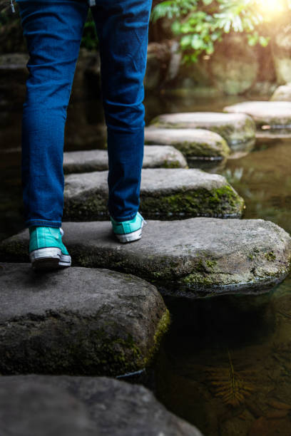 istock Woman legs walking on stepping stones 2205894351