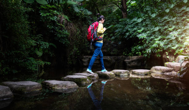 istock Female backpacker walking on stepping stones 2205894353