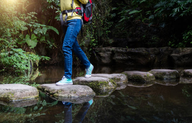 istock Female backpacker walking on stepping stones 2205894362