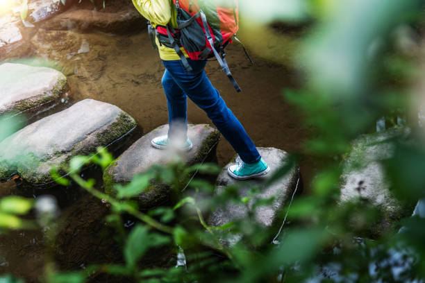 istock Female backpacker walking on stepping stones 2205894375