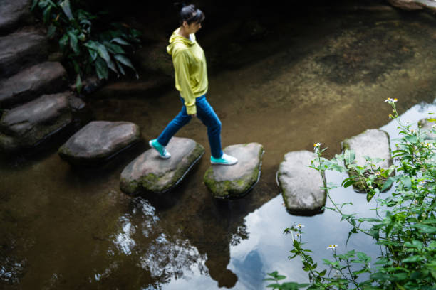 istock Woman walking on stepping stones 2205894380
