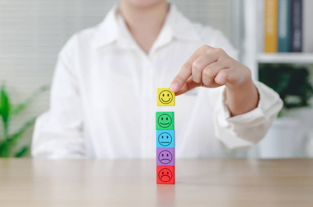 Customer Satisfaction and Feedback Concept. Woman arranging blocks with different smile faces representing customer satisfaction level, from unhappy to happy, feedback, and service quality improvement
