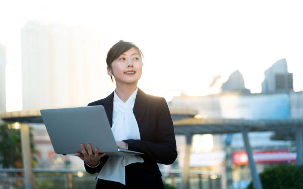 istock Businesswoman using laptop outside the office building 2205895414