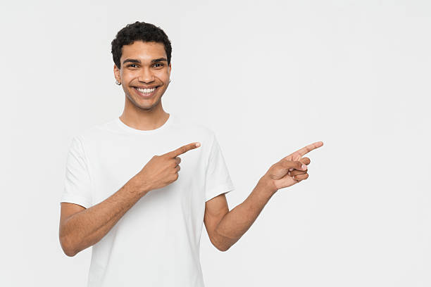Smiling Man in White T-Shirt Pointing Away on a White Background