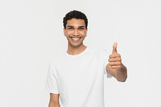 istock Young Man Smiling and Giving a Thumbs-Up Gesture in Studio 2205895555