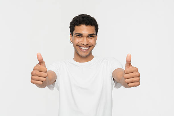 istock Smiling Man Giving Thumbs Up Gesture in a White Shirt 2205895557