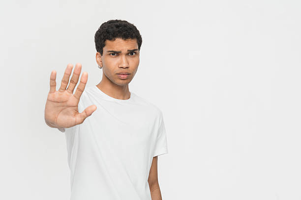 istock Young Man Gesturing With Raised Hand Against a White Background 2205895610