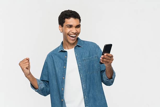 istock Excited Young Man Cheering While Reading on Smartphone in Casual Wear 2205895628