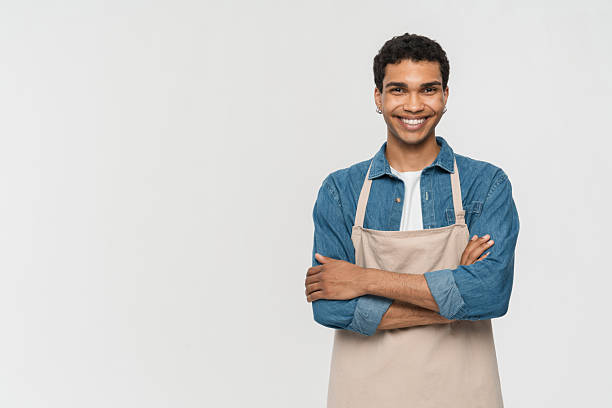istock Smiling Young Barista in Apron Posing Against White Background 2205895711