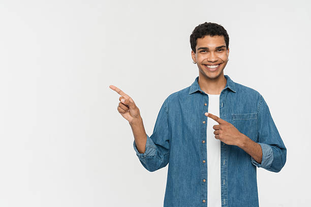 istock Smiling Young Man Pointing Sideways in Casual Blue Shirt 2205895757