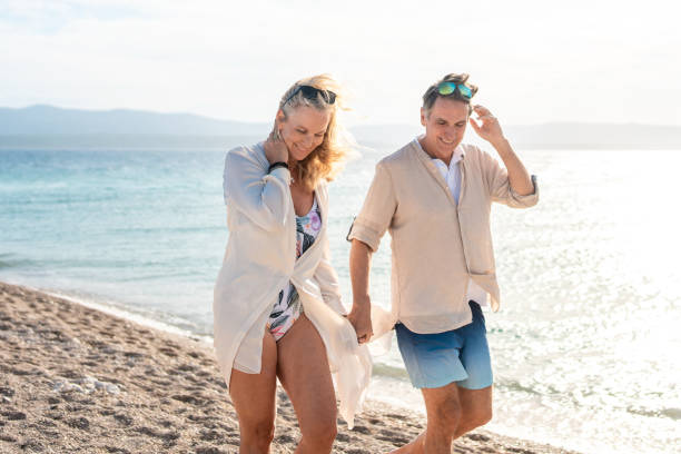 istock Relaxed Mature Caucasian Couple Strolling Along a Sunny Beach with Clear Blue Waters 2205896067