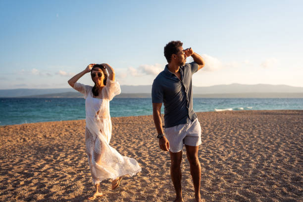 istock Romantic Couple Looking Into Distance On Sandy Beach At Golden Hour 2205896138