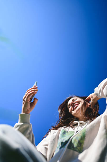 istock Young woman relaxing outdoors using mobile phone on sunny day 2205896244