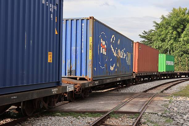 Perak, Malaysia - December 28, 2024 : \n Colorful freight train with blue, red, green containers on tracks in an inland port, surrounded by lush greenery, perfect for logistics and transportation themes.