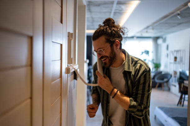 istock Cheerful young man answering intercom call at home 2205899778