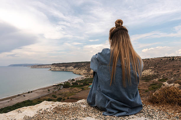 Young Woman Enjoying Peaceful Coastal View from a Cliff.
