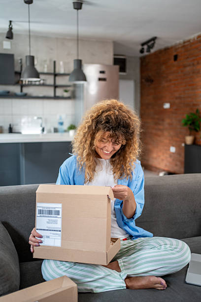 istock Happy woman opening a package at home 2205905343