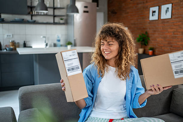 istock Young woman holding two parcels sitting on sofa at home 2205905519