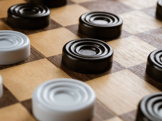 istock Checkers game setup on a checkered board. Strategy, game pieces, black and red, ready to play, board game. 2205906655