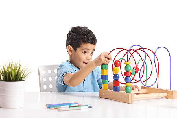 Boy sitting and playing with a logic toy bead maze isolated on white background