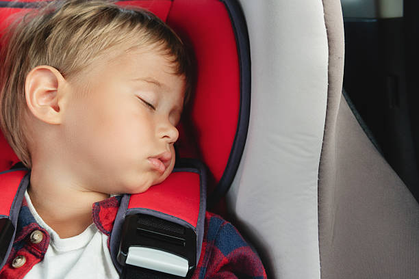 istock Adorable boy peacefully sleeping in  a car seat inside a vehicle 2205908095