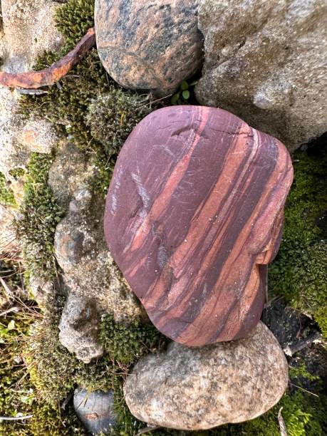 istock Striped Red Stone Among Mossy Rocks 2205908336