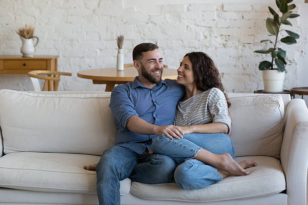istock Joyful married couple relaxing on soft white home couch together 2205909150