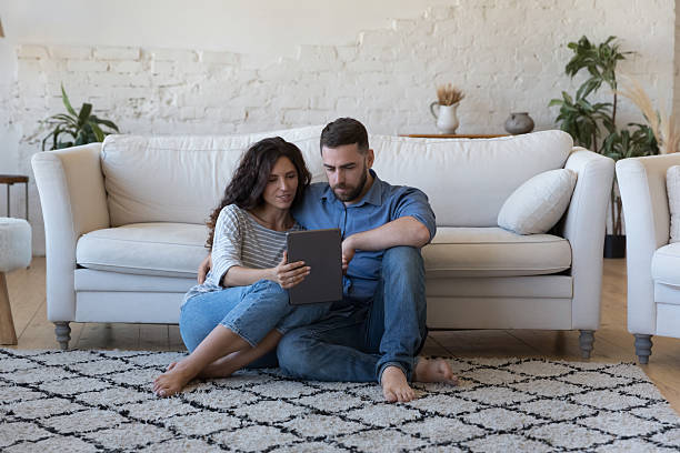istock Focused husband and wife sharing digital device at home together 2205912188