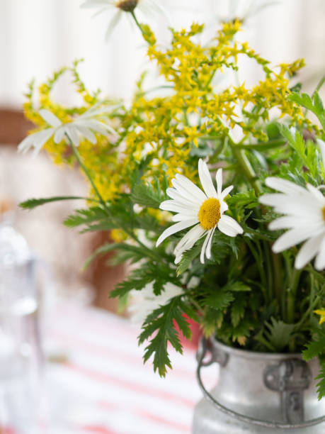 Bouquet of daisies and yellow flowers bringing joy to rustic table setting