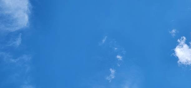 Under an open sky, white clouds stretch gently, shaping silhouettes that change every moment. The interplay of light and shadow on their edges highlights their ethereal texture, creating a subtle and ever-renewing spectacle.