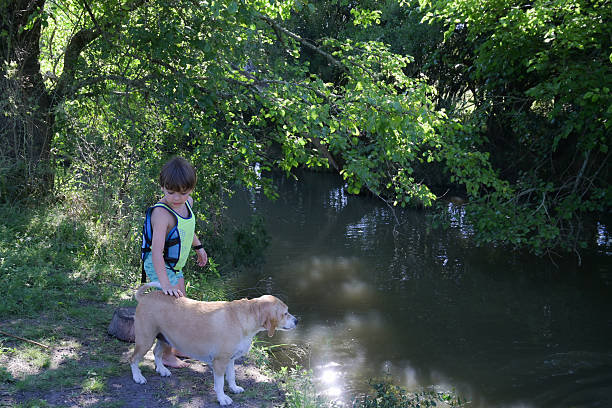 kid with his dog in the river on summer