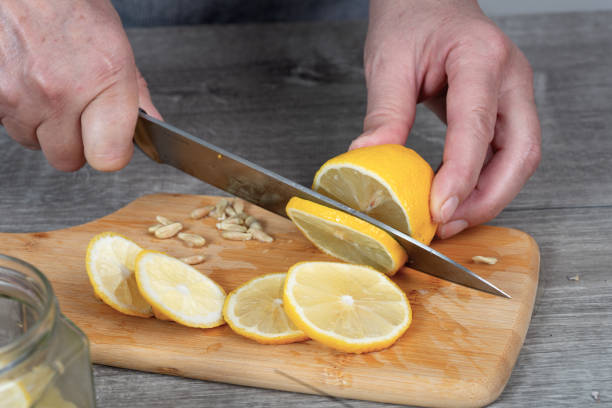 istock woman's hands cut lemon with a knife on a cutting board. Preparing for canning. 2205923697