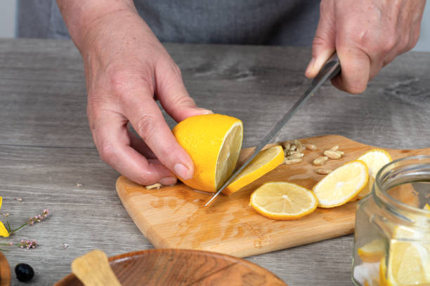 istock woman's hands cut lemon with a knife on a cutting board. Preparing for canning. 2205923723