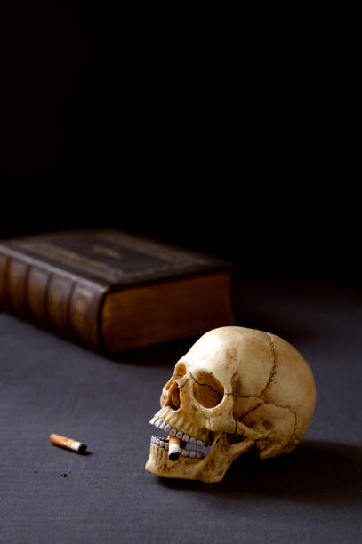 istock Artificial realistic human skull smoking a cigarette Copy space. Dark background 2205923734