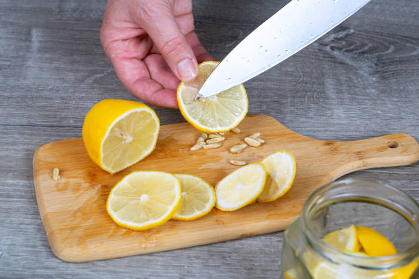 istock woman's hand cuts and peels a lemon with a knife. Close-up. 2205923781