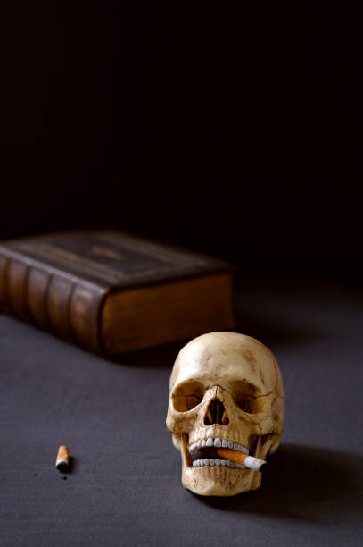 istock Artificial realistic human skull smoking a cigarette Copy space. Dark background 2205923845