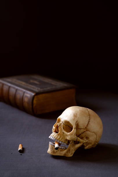 istock Artificial realistic human skull smoking a cigarette Copy space. Dark background 2205923989