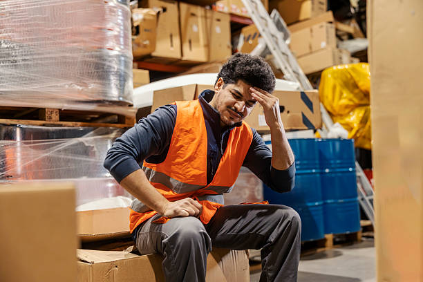 istock Interracial storage worker in pain sitting on boxes in warehouse and having bad headache. 2205924291