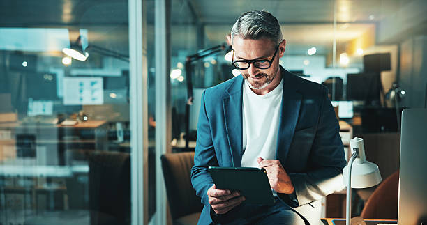 istock Mature programmer, tablet and review with project, feedback or overtime work for research. Web design, night or email update for man, software agency and b2b networking or online communication 2205924356