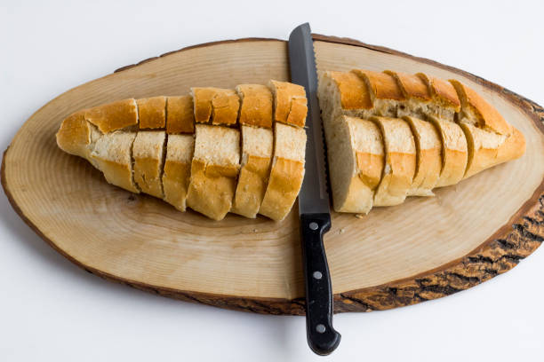 Close-up taken of sliced bread on the natural wooden board with bread knife,at the white ground.