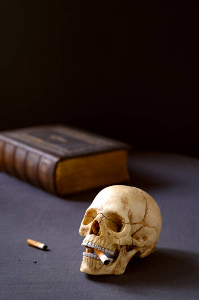 istock Artificial realistic human skull smoking a cigarette Copy space. Dark background 2205924997