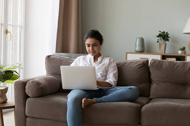istock Attractive Indian woman sit on sofa with laptop 2205925102