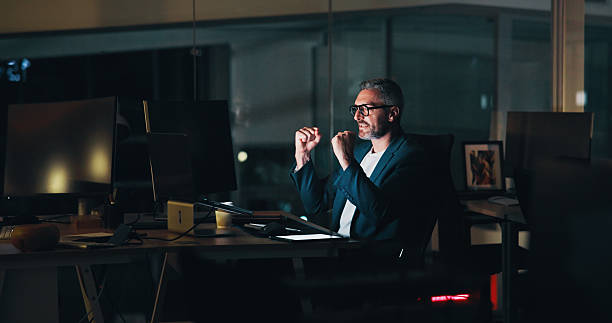 istock Business, man or celebration with laptop in office for system update success, troubleshooting or software debug. Web developer, mature person and excited for website maintenance or UI design at night 2205925522