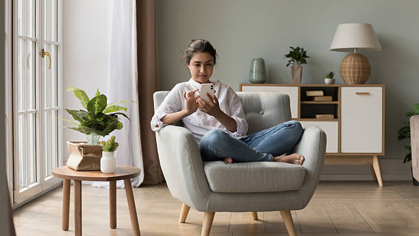 istock Indian woman relaxing on armchair using cellphone chatting online 2205926123