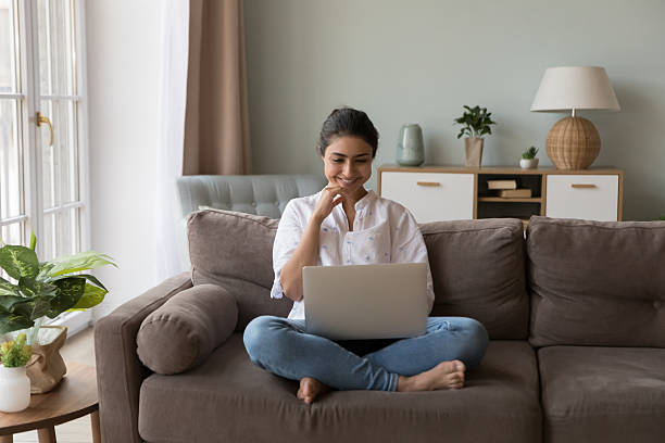 istock Smiling Indian woman spend weekend leisure at home using laptop 2205926970